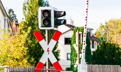 Das Foto zeigt einen beschrankten Bahnübergang mit einer Ampel und einem Andreas-Kreuz-Verkehrsschild