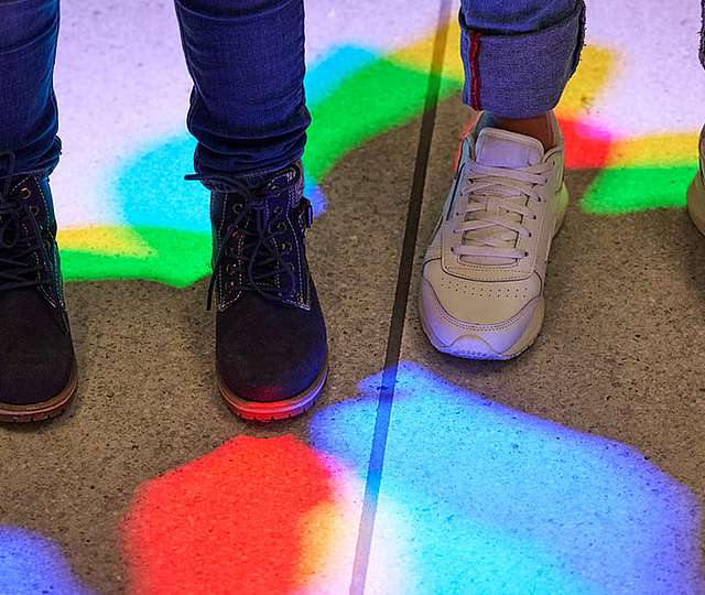 Zwei Paar Füße stehen im Licht von RGB-Lichtspots.