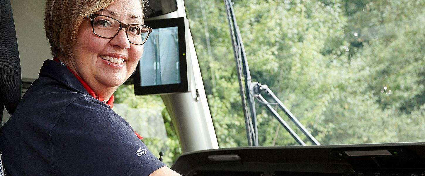 Eine Frau sitzt lächelnd im Führerstand einer Stadtbahn.