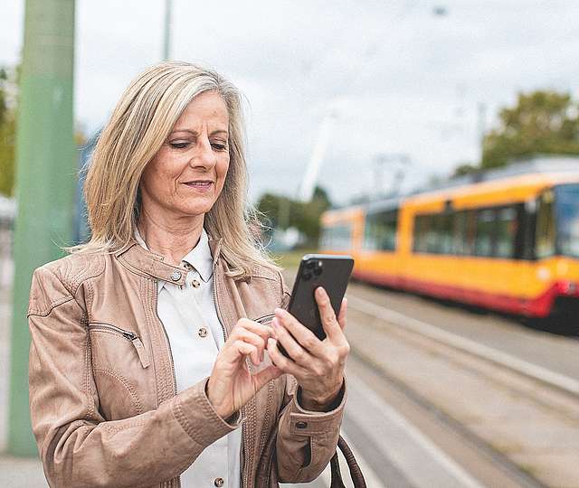 Frau steht mit Bandy vor der Bahn